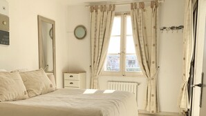 Un dormitorio con una cama grande, una mesita de noche, un espejo y una ventana con cortinas.