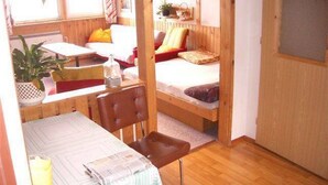 Una habitación compacta con literas, una mesita con una silla y una ventana con cortinas.