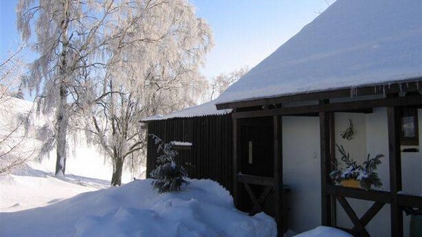 Un edificio cubierto de nieve con fachada de madera y un porche techado.