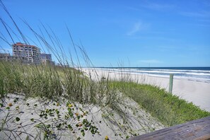 A beach with sand dunes and a wooden boardwalk.