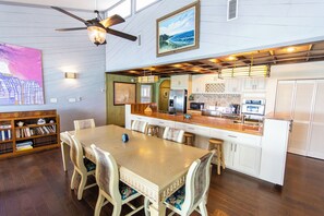 A spacious kitchen with modern appliances, a dining area with a wooden table and chairs, and a ceiling fan.