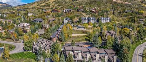 A residential area with multiple two-story houses, a winding road, and a mountainous backdrop.