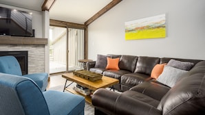 A modern living room with a leather sofa, a blue armchair, and a wooden coffee table. - Hot Tub /Pool! Fireplace! Walk to Slopes! (Steamboat Springs)