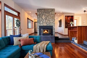Una sala de estar con chimenea de piedra, un sofá azul y una mesa de centro de madera.