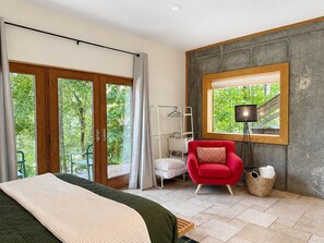 A bedroom with a bed, a red chair, a window with a view of greenery, and a floor lamp. - Artful Self Restoration! Japanese Tub. Fireplace (Bakersville)
