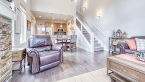 A spacious living room with a leather sofa, a wooden coffee table, and a staircase leading to the upper floor.