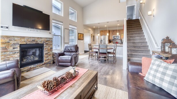 A spacious living room with a fireplace, leather furniture, and a dining area with a kitchen in the background.
