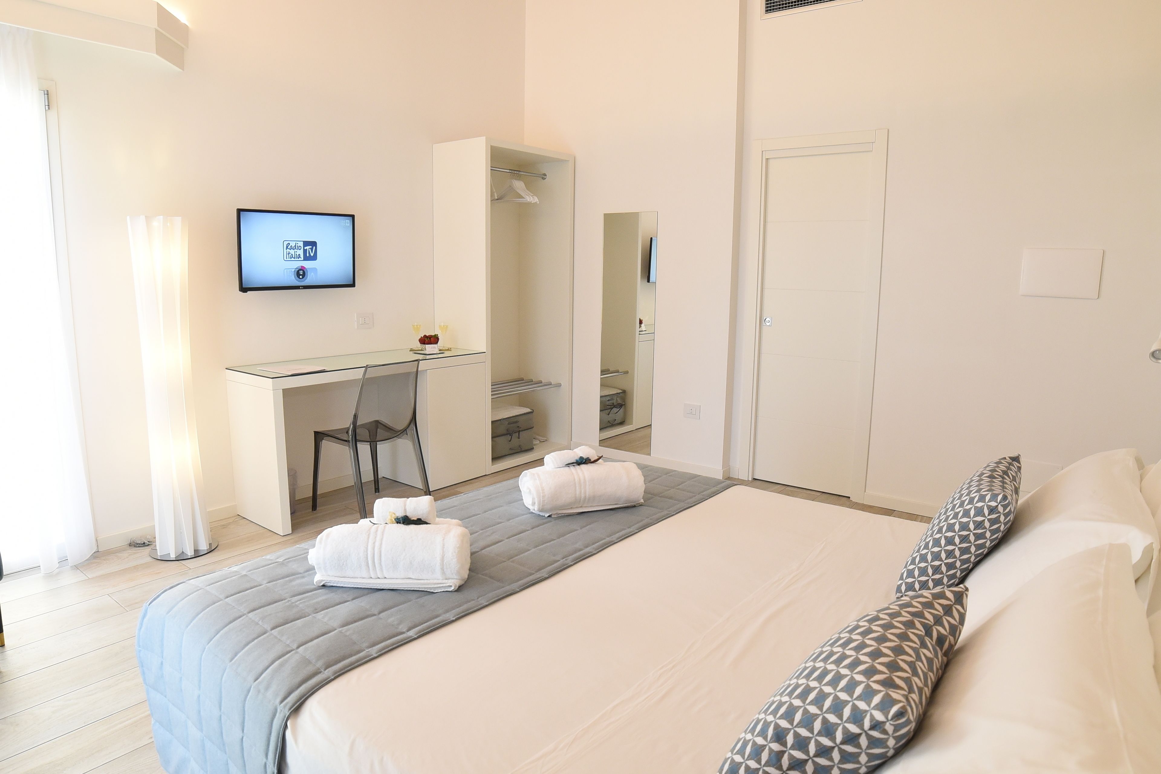 A hotel room with a bed, a desk, a chair, a TV, and a bathroom.