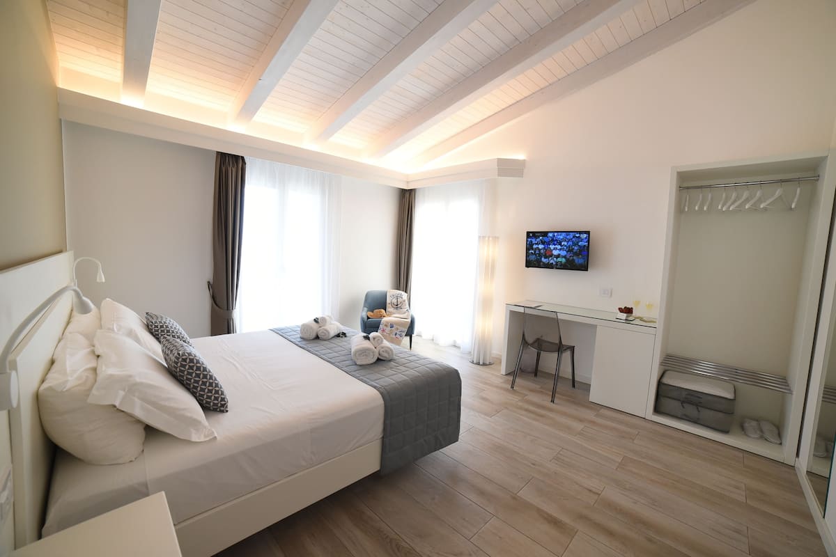 Een moderne hotelkamer met een groot bed, een bureau, een televisie en een inloopkast.