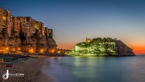 Un pueblo costero con edificios históricos, una playa y un acantilado con un pequeño asentamiento.