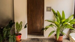A wooden door with a number '2' sign above it, flanked by potted plants. - Casita Los Tecolotes (Antigua Guatemala)