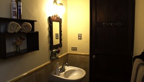 A bathroom with a sink, mirror, towel rack, and a door.