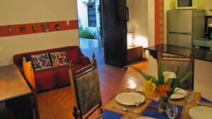 A dining area with a table set for two, a red sofa, and a view of the outside. - Casita La Esquina (Antigua Guatemala)