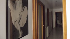 A hallway with a framed artwork on the wall, wooden doors, and a radiator. - B&B Salita Metello (Agrigento)