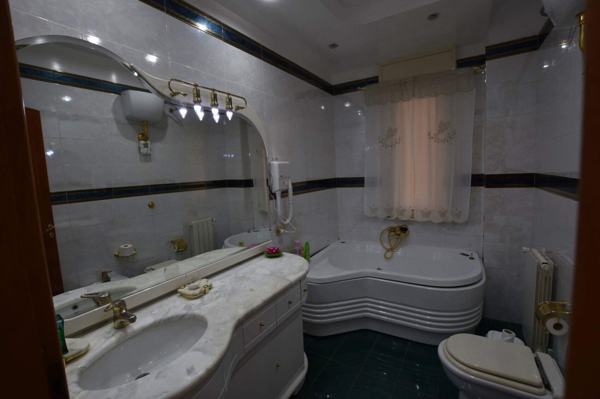 Une salle de bain avec un grand miroir, un lavabo, des toilettes et une baignoire.