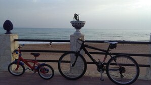 A beachside view with a bicycle and a red tricycle parked on a paved area, overlooking the ocean. - B&B Salita Metello (Agrigento)