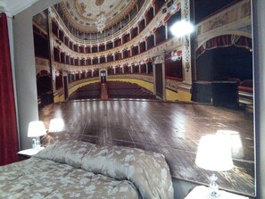 Un teatro con un escenario central, varios balcones y elaboradas decoraciones en el techo.
