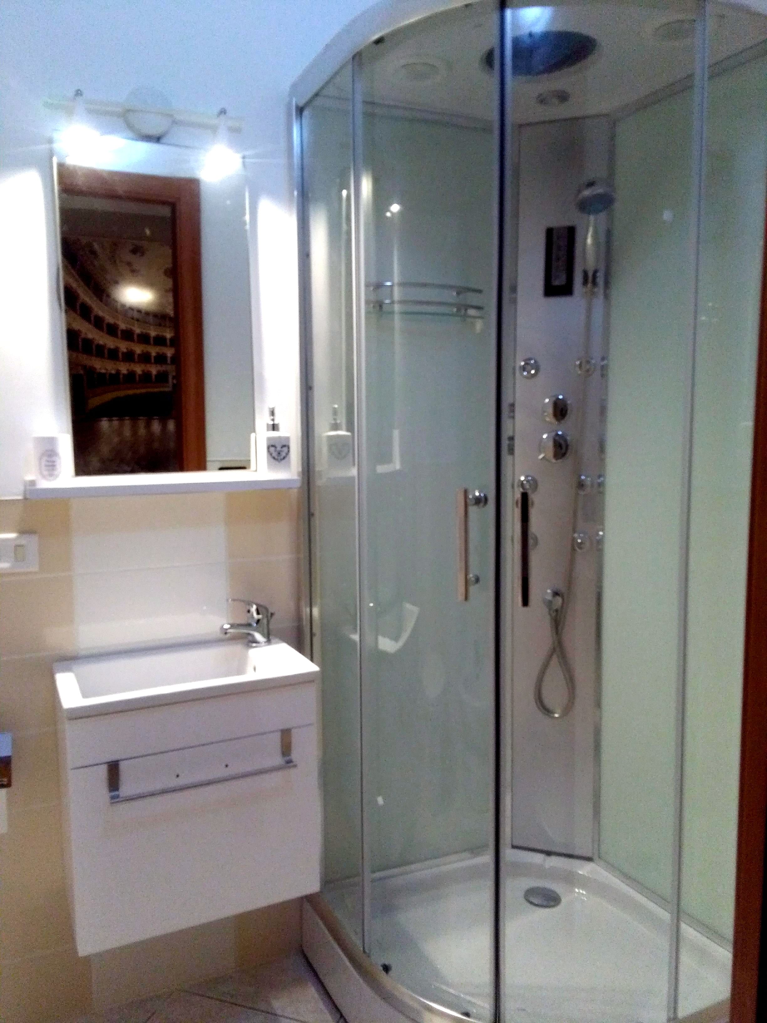 Ein Badezimmer mit Duschkabine, Waschbecken und Spiegel.