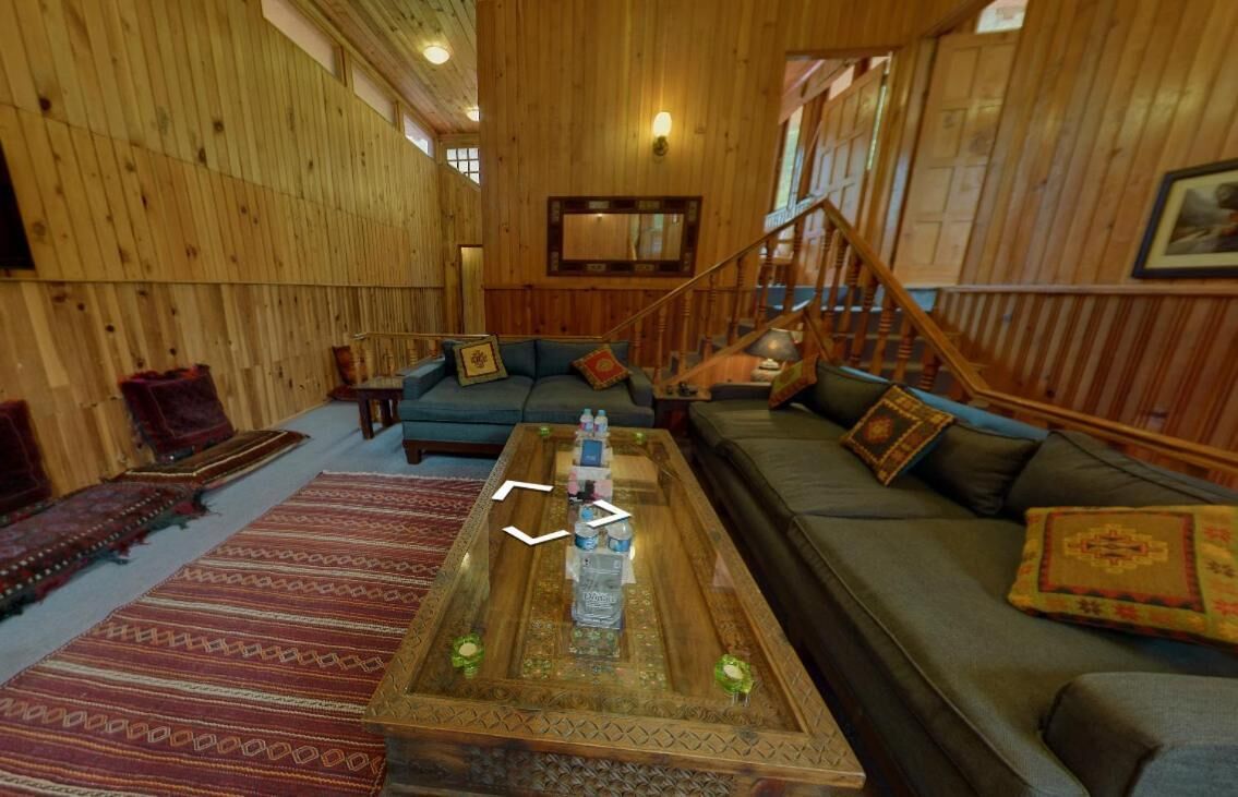 A wooden interior with a sofa, a coffee table, and a staircase.