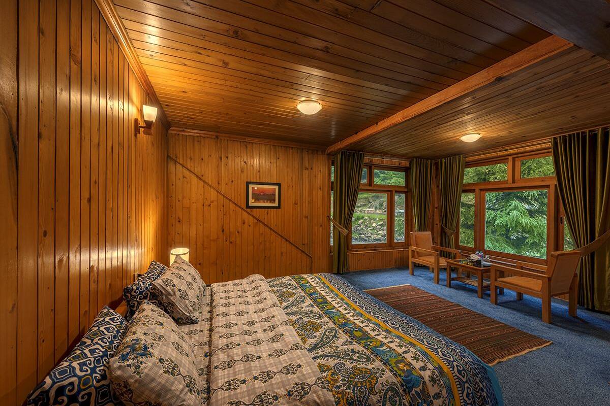 Quarto com painéis de madeira, uma cama, uma escrivaninha e uma janela com cortinas.