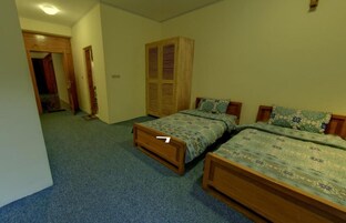 Un dormitorio con dos camas individuales, un armario de madera y suelo alfombrado.
