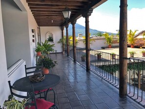 A covered outdoor patio with a table and chairs, potted plants, and a view of the landscape. - Casita El Huipil (Antigua Guatemala)