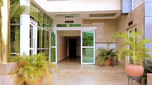 A hotel entrance with a glass door, potted plants, and a sign indicating the entrance.