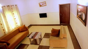 A living room with a sofa, a coffee table, a TV, and a door.