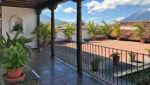 A covered outdoor area with potted plants, a tiled floor, and a view of a mountain. - Casita Buena Vista (Antigua Guatemala)