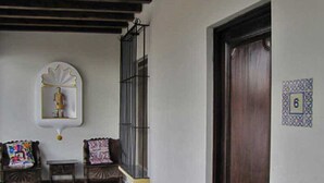 A small porch with a wooden bench, a small table, and a wall-mounted decorative item. - Casita Buena Vista (Antigua Guatemala)