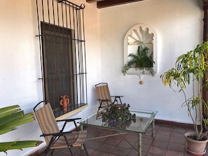 A patio with two chairs, a glass table, a potted plant, and a decorative mirror. - Casita Buena Vista (Antigua Guatemala)