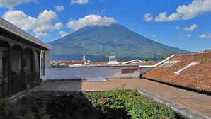 A building with a tiled roof and a view of a mountain. - Casita Buena Vista (Antigua Guatemala)