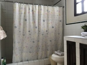 A bathroom with a floral shower curtain, a toilet, and a sink with a towel on it.
