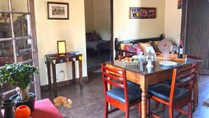 A dining area with a wooden table and chairs, a potted plant, and a small table with a lamp. - Casita El Balcón (Antigua Guatemala)