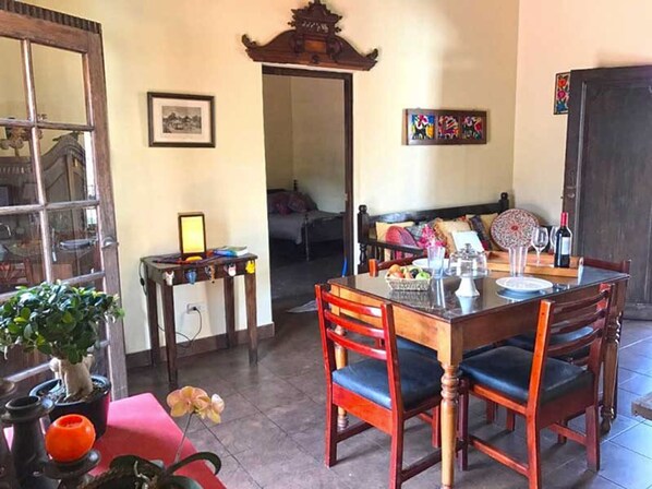 A dining area with a wooden table and chairs, a potted plant, and a small table with a lamp.