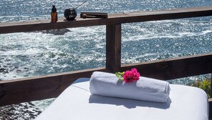 A spa area with a view of the ocean, a wooden deck, and a towel with a flower.