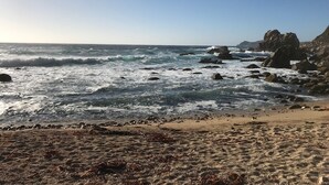 A beach with rocky outcrops and waves crashing onto the shore.