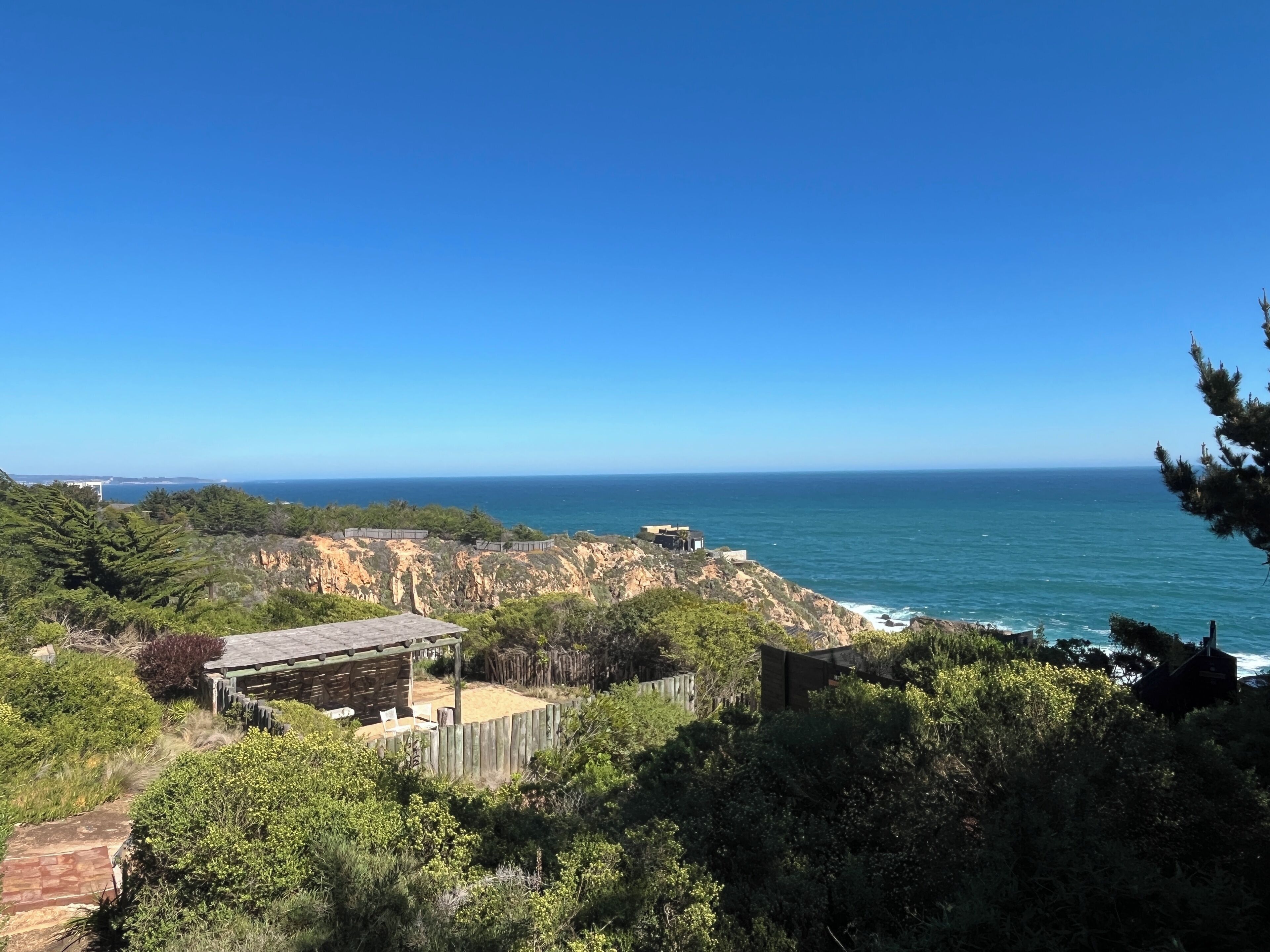 A coastal property with a wooden deck, a small building, and a view of the ocean.