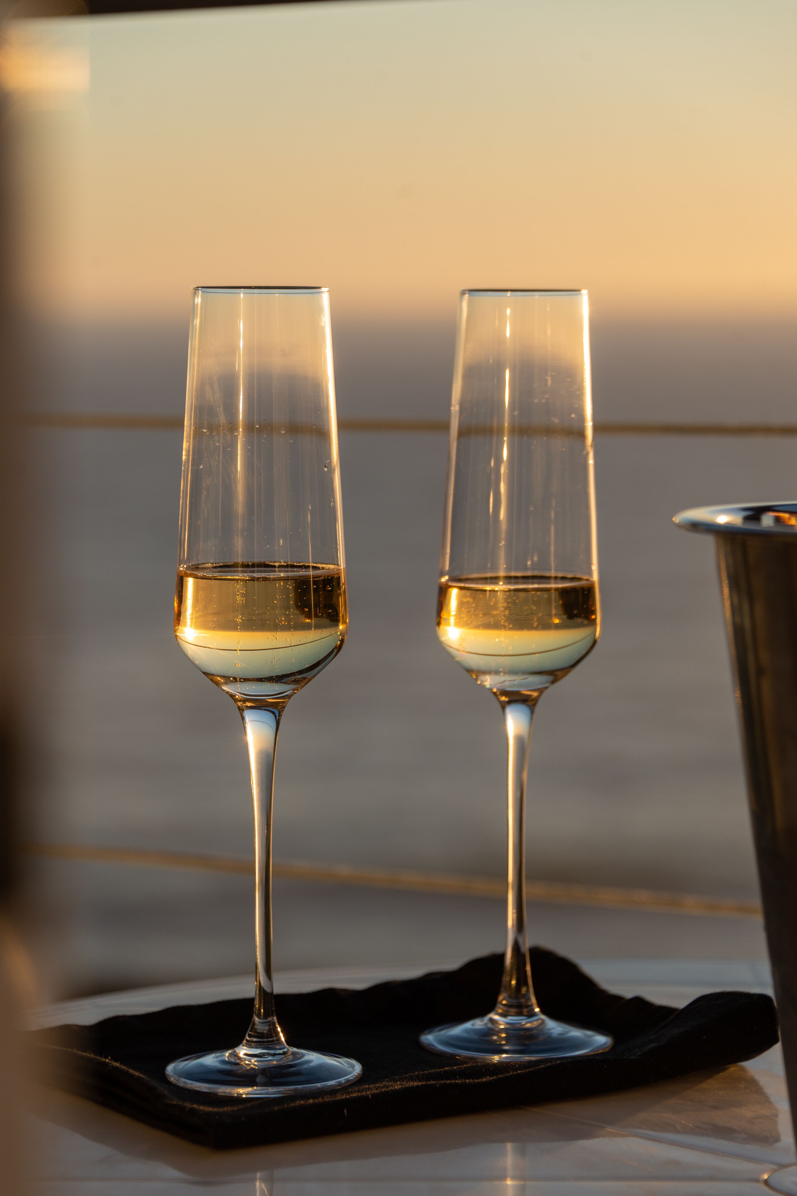 Two glasses of white wine on a black cloth.