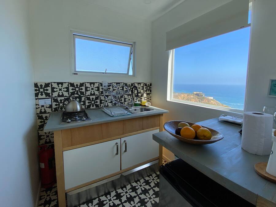 Una cocina con vista al mar, una estufa a gas, un fregadero y un tazón de fruta en la encimera.