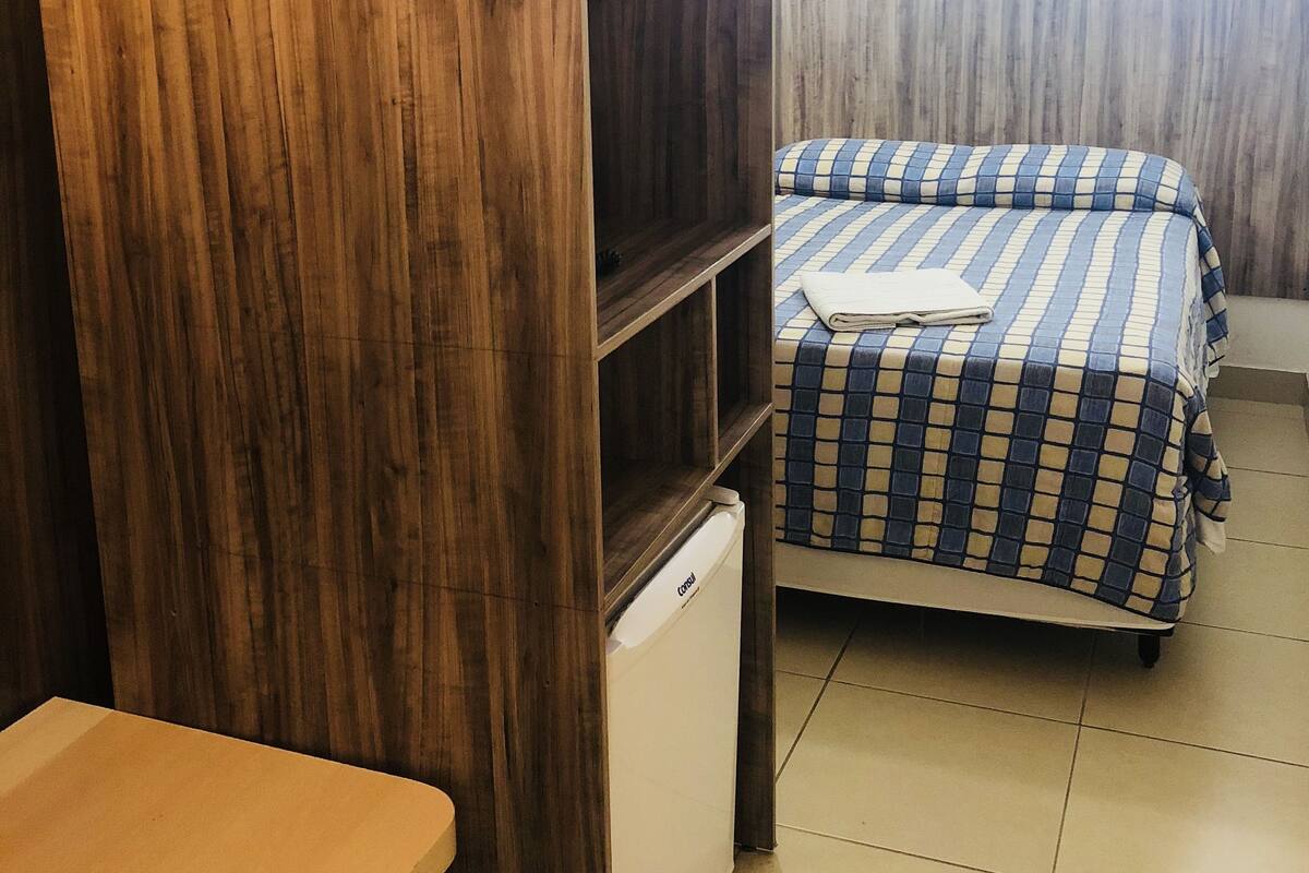 A compact room with a bed, a small table, and a compact refrigerator.