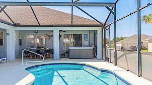 Une piscine extérieure couverte avec un jacuzzi, une terrasse dotée de chaises et une vue sur le quartier.