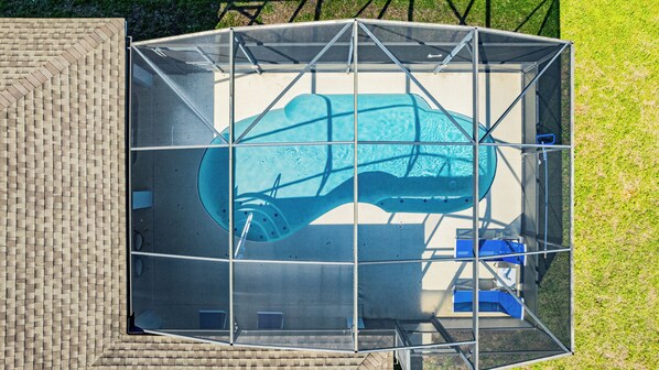 Une piscine dotée d’une structure en métal, entourée d’un mur en briques et d’une pelouse.