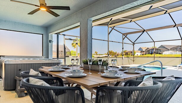 Un espace extérieur aménagé pour les repas, avec un jacuzzi, des fauteuils en osier et une vue sur le paysage environnant.