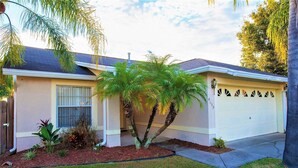 A single-story house with a garage, a small front yard with a palm tree, and a well-maintained lawn.