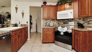 A kitchen with wooden cabinets, a microwave, an oven, and a sink.