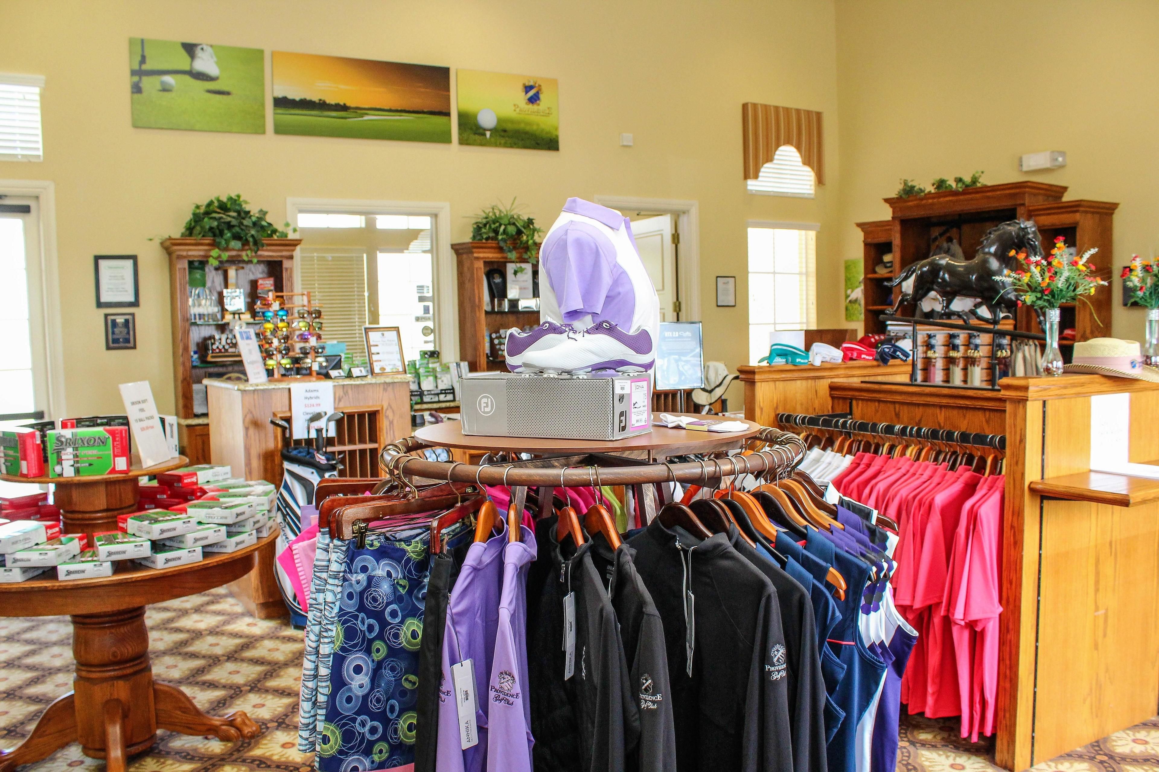 A retail space with clothing racks, a display table with products, and a wooden counter.