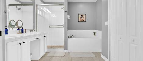 A modern bathroom with a white vanity, a large mirror, a bathtub, and a shower.