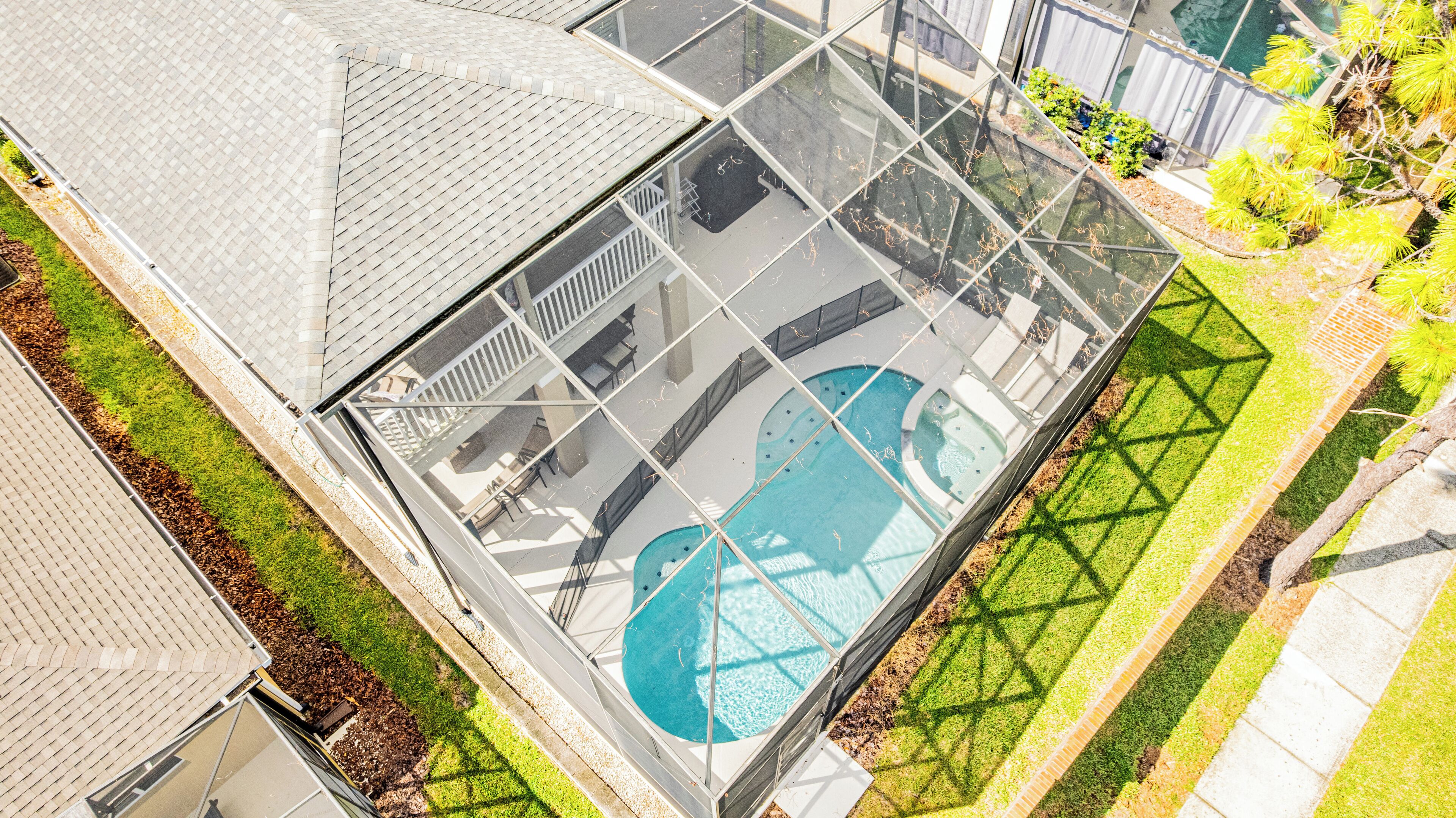 A rooftop pool with a glass enclosure, surrounded by a well-maintained lawn and a small garden area.