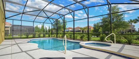Una piscina interior con agua cristalina y azul, rodeada por un recinto de vidrio y dos sillones de descanso.